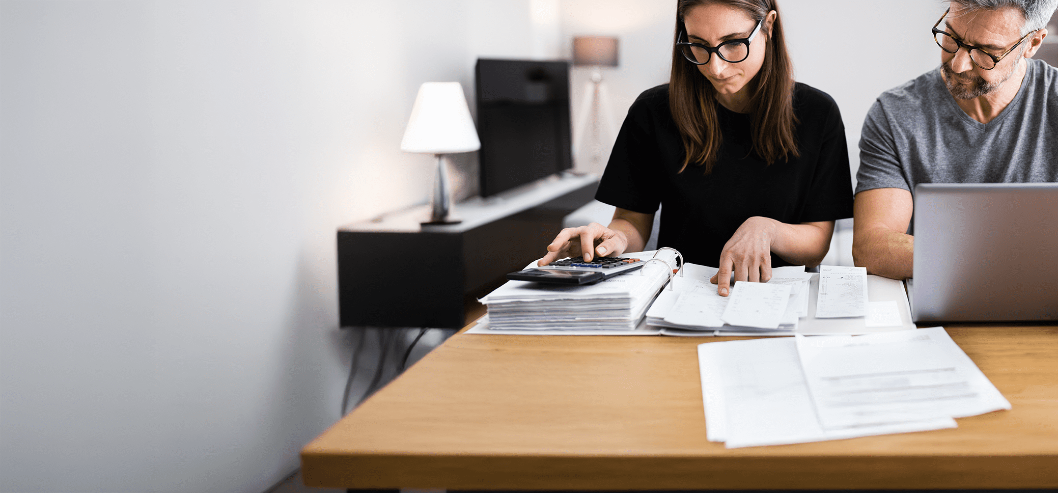 man and woman looking at files and a calculator